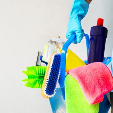 Man holding mop and plastic bucket with brushes, gloves and detergents in the kitchen